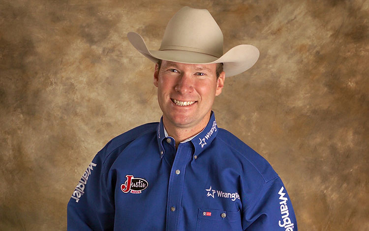 A cowboy, Wayne Brooks, wearing a blue shirt and smiling.